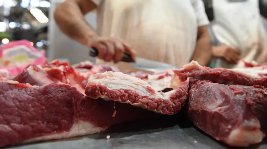 Hombre cortando carne en una carnicería